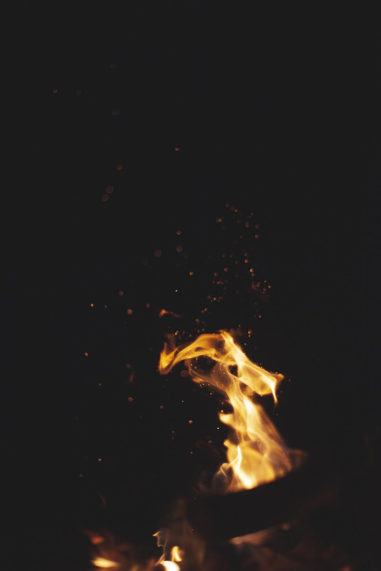 Flammen und Funken eines Feuers vor dunklem Hintergrund.