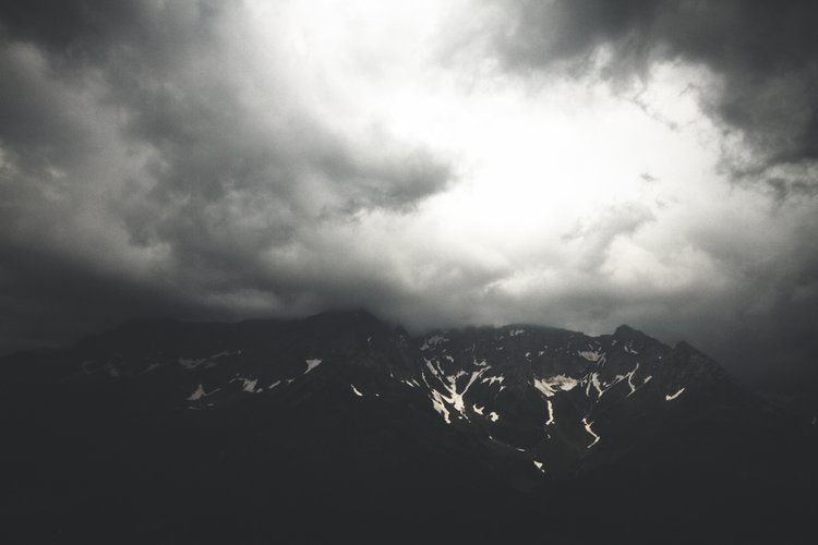 Dunkle Wolken über schneebedeckten Bergen.