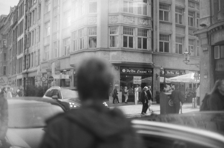 Schwarzweiße Straßenszene vor Hana Cuisine und Hana Bar mit Passanten und geparkten Autos.