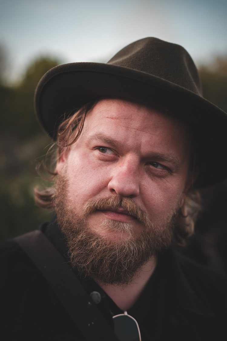 Selbstporträt von Arnar mit dunklem Hut im Freien.