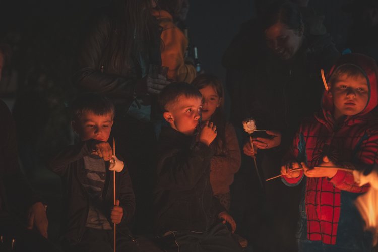 Children and adults roasting marshmallows by the fire.