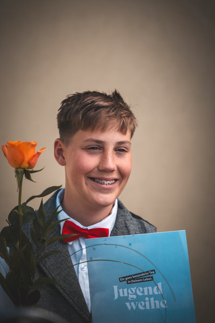 Ein lachender Junge mit einer Rose und einem Erinnerungsbuch.