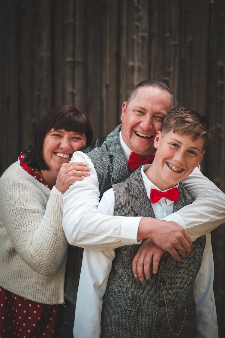 Drei Familienmitglieder lachen und umarmen sich.