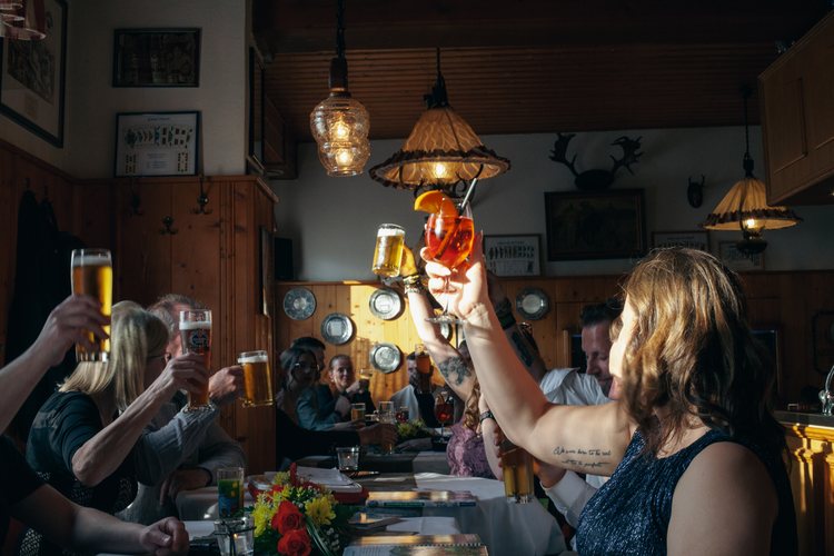 Hochzeitsgäste stoßen gemeinsam am Tisch an.