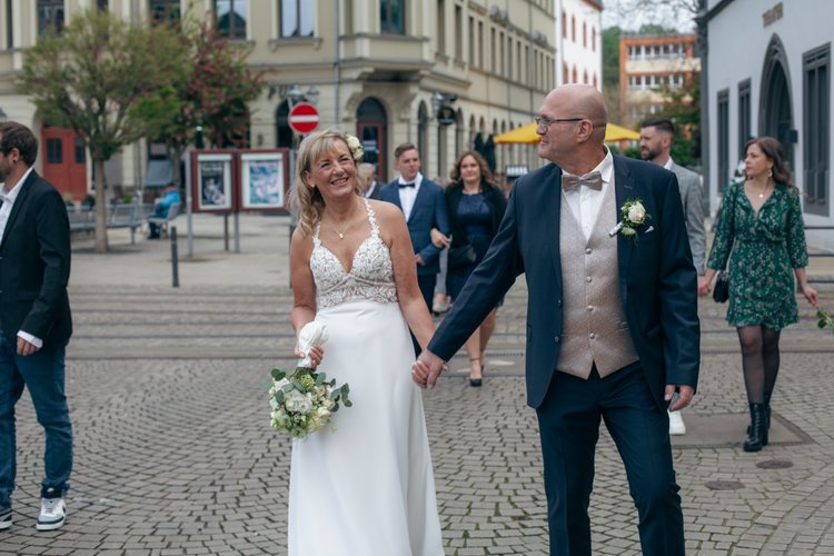 Das Hochzeitspaar geht Hand in Hand durch die Stadt.